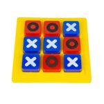 A young boy and his grandfather smiling and playing the KidNzo 3D Tic Tac Toe board game together on a wooden coffee table, using chunky blue and red blocks.