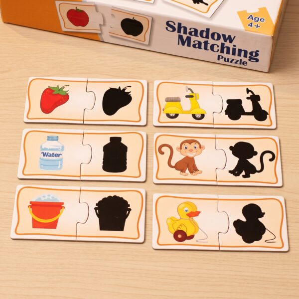 A young boy sitting at a wooden desk, focused on assembling KidNzo Shadow Matching 2-piece puzzles, pairing colorful objects like a frog and helicopter to their silhouettes.